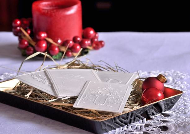 Polish traditional Christmas wafer on hay. Red candle in the background.